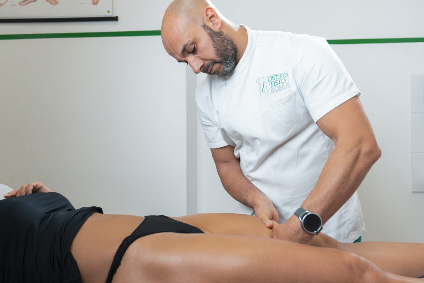 Il massoterapista pratica un massaggio di linfodrenaggio manuale a roma sulle gambe della paziente nello studio di osteofisioroma